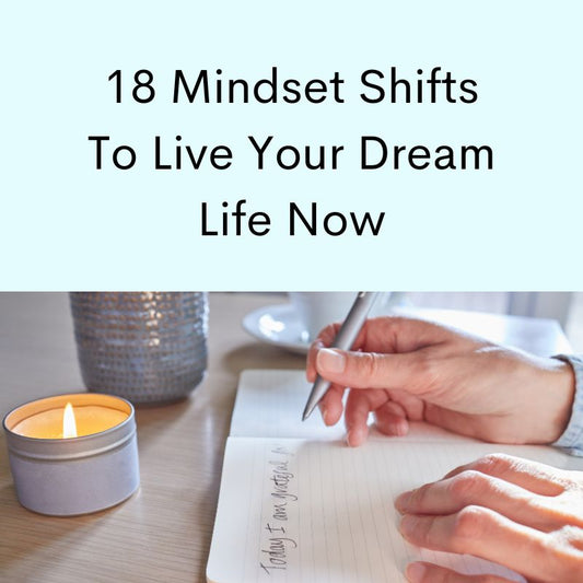 Hand holding pen, open journal, candle burning.