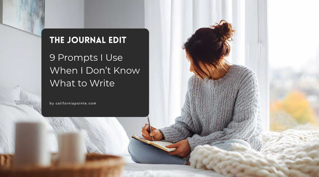 Woman in gray sweater, sitting on a white blanket, writing in a journal.